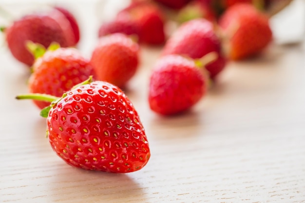 Fruta de fresa madura roja orgánica fresca sobre fondo de madera primer plano