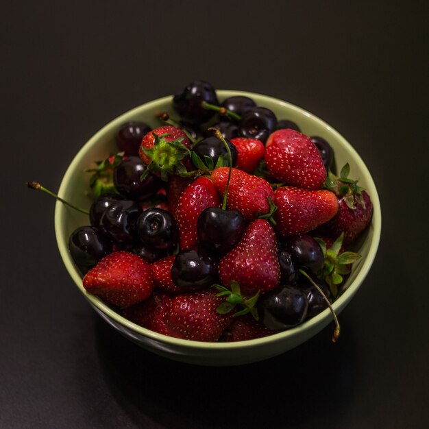 Fruta fresca de morangos e cerejas em um copo