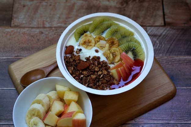 Fruta fresca y granola con yogur en un recipiente sobre una mesa de madera