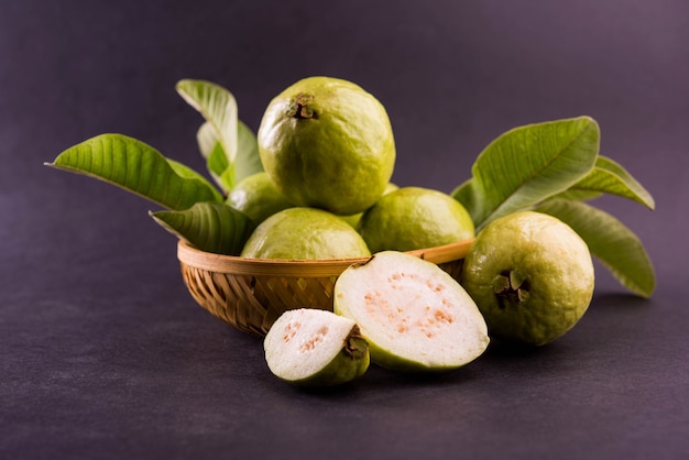 Fruta fresca de guayaba verde también conocida como Amrood en hindi y Perú en marathi, servida en una canasta entera o en rodajas sobre un fondo de colores. Enfoque selectivo