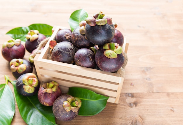 Fruta fresca de mangostán en la cesta en la mesa de madera