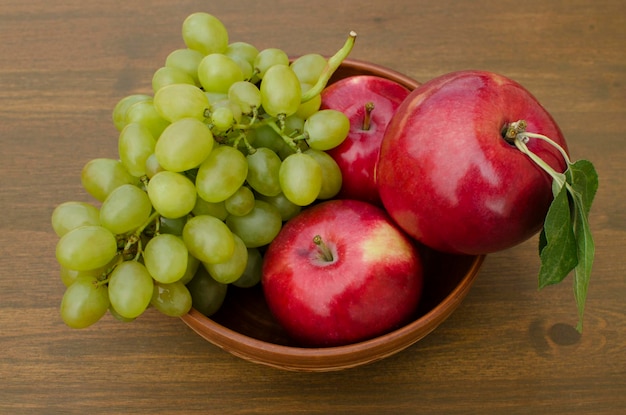 Fruta fresca Manzanas rojas y uvas en un plato sobre la mesa closeup Bodegón de fondo