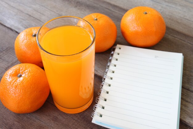 fruta fresca de naranja colocada en el piso de madera y tener jugo de vidrio