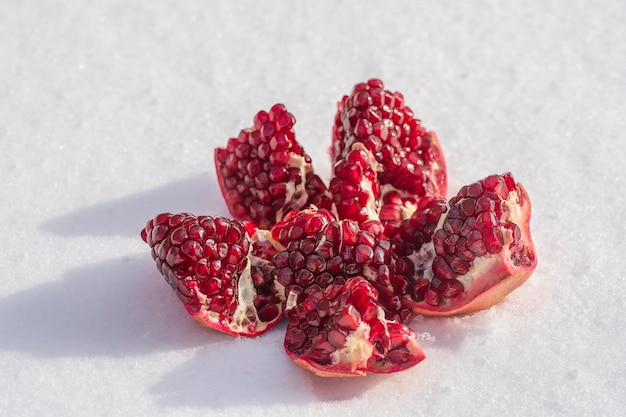 Fruta de granada abierta con semillas rojas en una nieve blanca en invierno de cerca