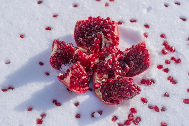 Fruta de granada abierta con semillas rojas en una nieve blanca en invierno de cerca