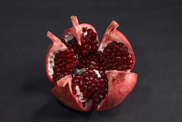 Fruta de granada bellamente cortada en una mesa de piedra negra