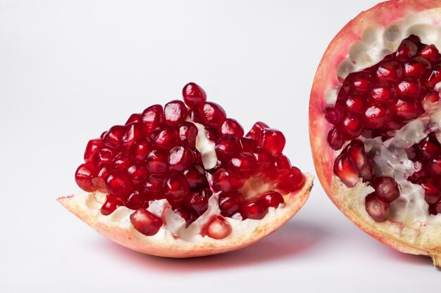 Fruta de granada madura rota sobre una superficie blanca.