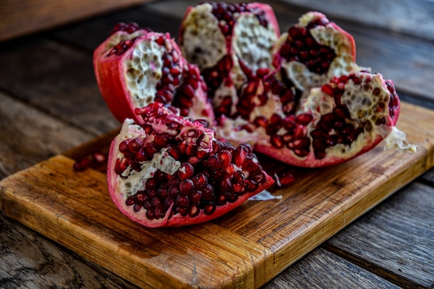 La fruta de la granada pelada en rodajas se encuentra sobre una placa de cocina sobre una mesa de madera