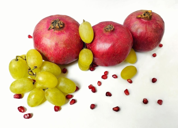 Fruta de granada y uvas sobre un fondo blanco alrededor de un foco selectivo de capullo de granada