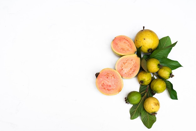 Fruta de guayaba madura con hojas sobre fondo blanco con espacio de copia