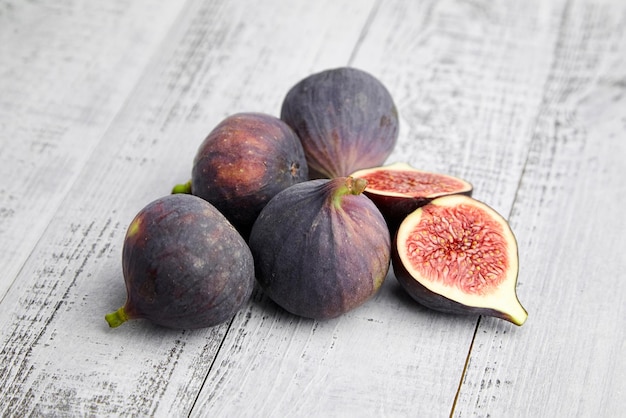 Fruta de higo con mitades maduras rojas sobre mesa de madera