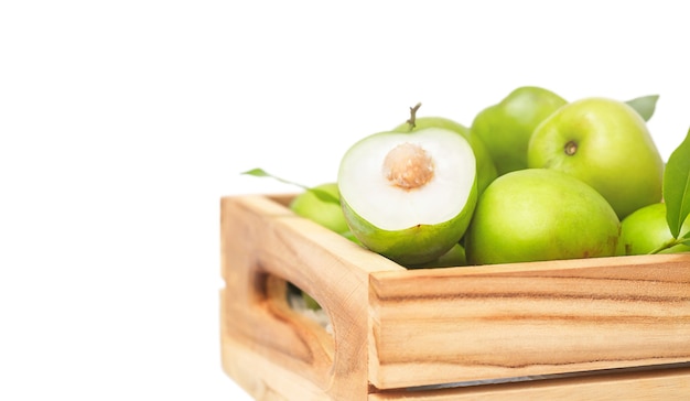 Fruta de jojoba verde y cortar la mitad en la caja de madera aislada sobre fondo blanco