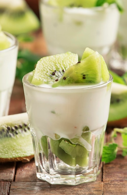 Fruta de kiwi con postre de yogur cremoso en vidrio antiguo enfoque selectivo de fondo de mesa de cocina de madera