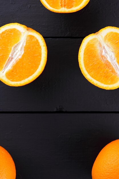 Fruta laranja em fundo preto de madeira Metades de laranjas em tábuas de madeira Copie o espaço