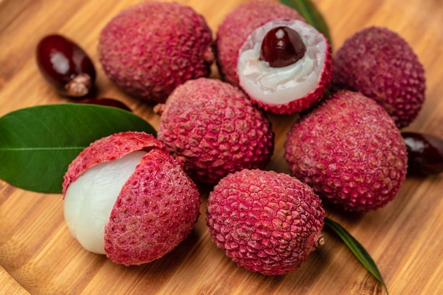 Foto fruta de lichi madura fresca y lichi pelado en una vista superior de la receta del menú de banner de fondo de madera