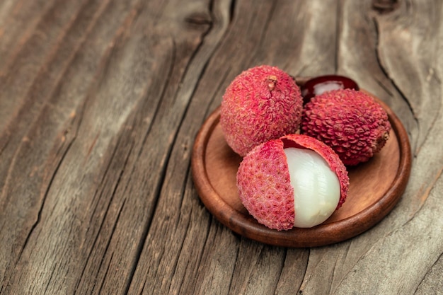 Foto fruta de lichi madura fresca y lichi pelado en una vista superior de la receta del menú de banner de fondo de madera