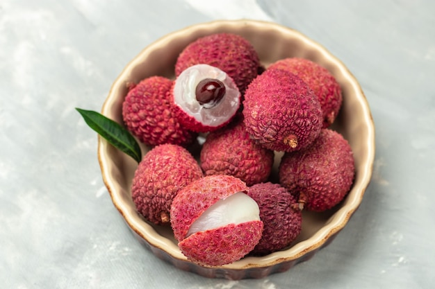 Fruta de lichi orgánica fresca en un plato sobre una vista superior de fondo claro