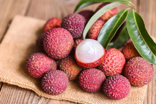 Fruta de lichi en saco con hoja verde y fondo de madera lichi maduro fresco pelado del árbol de lichi en fruta tropical Tailandia en verano