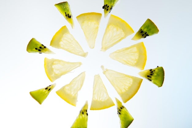 Fruta limón y kiwi cortado en rodajas sobre fondo blanco.