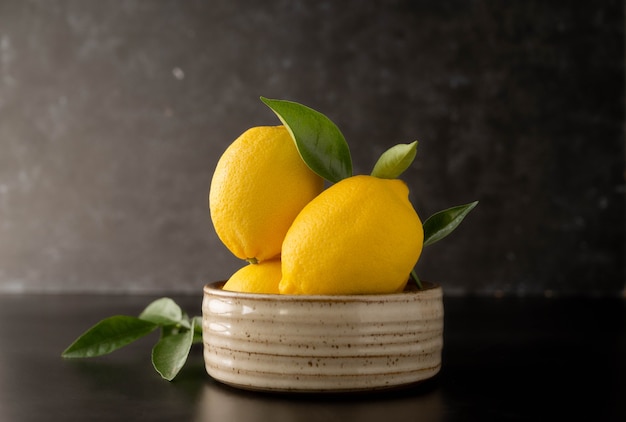 Fruta de limones frescos sobre fondo negro oscuro en un recipiente