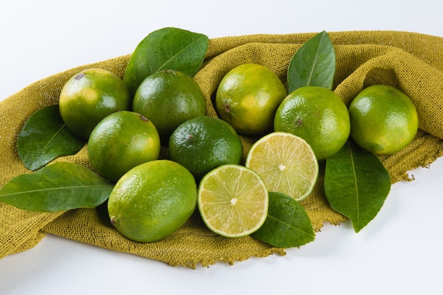 Fruta madura de limón verde sobre superficie blanca.