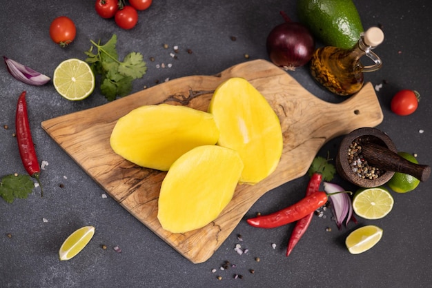 Fruta de mango tropical en rodajas peladas en una tabla de cortar de madera