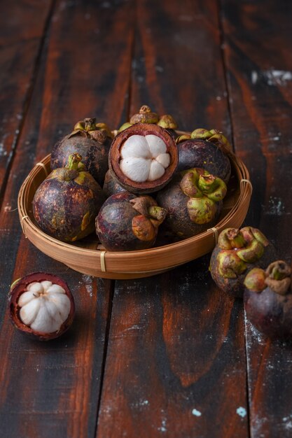 Fruta de mangostán en canasta de bambú sobre mesa de madera