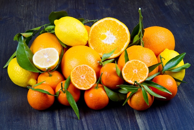 Fruta naranja, mandarinas frescas, naranjas y cítricos sobre madera.