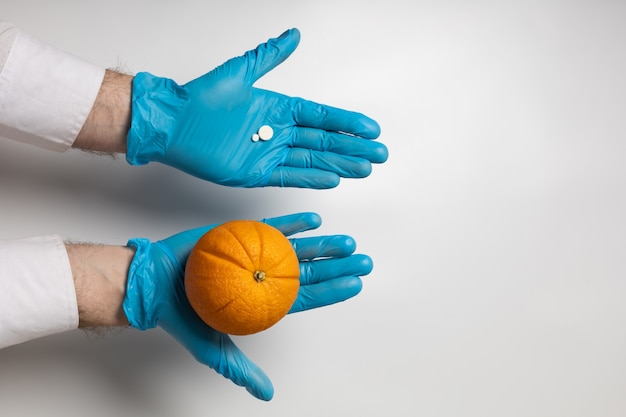 Fruta naranja y píldora en manos