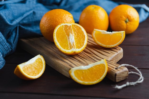 Fruta de naranjas en rodajas cerca de textil de mezclilla en tablero de madera Concepto mínimo de cítricos de frutas jugosas de naranja