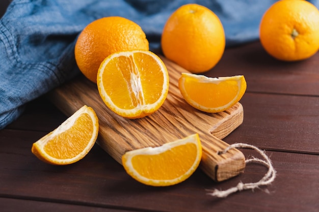 Fruta de naranjas en rodajas cerca de textil de mezclilla en tablero de madera Concepto mínimo de cítricos de frutas jugosas de naranja