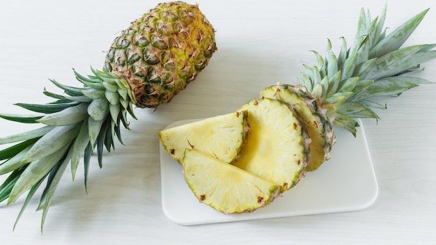 Fruta de piña fresca en rodajas sobre fondo blanco de madera