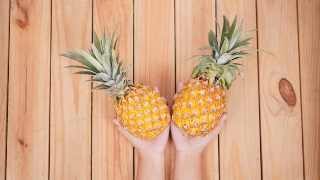 Fruta de piña en la palma sobre un fondo de madera