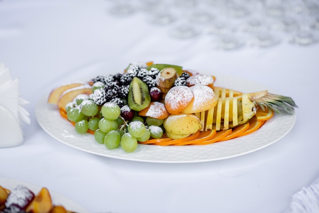 Fruta en rodajas en un plato blanco espolvoreado con azúcar glas