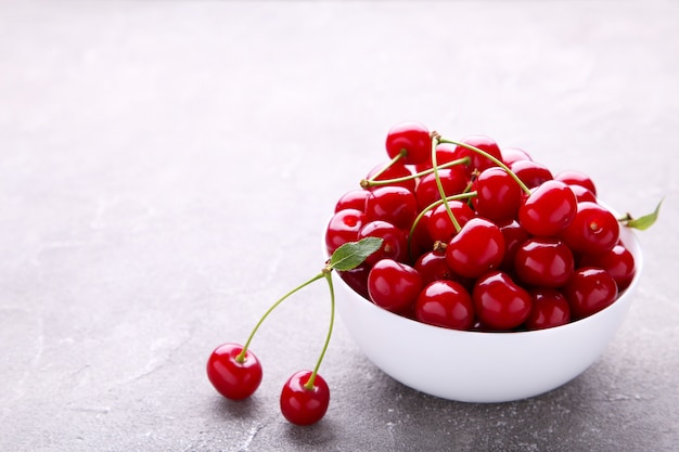 Fruta roja fresca de la cereza en placa en el hormigón gris