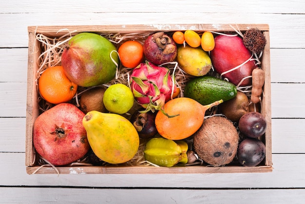 Fruta tropical en una caja de madera Papaya Dragon Fruit rambután tamarindo cactus fruta aguacate granadilla carambola kumquat mango mangostán maracuyá coco