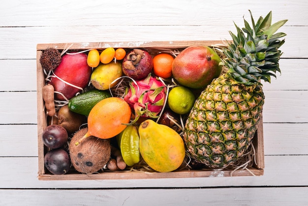 Fruta tropical en caja de madera. Papaya, fruta del dragón, rambután, tamarindo, fruta de nopal, aguacate, granadilla, carambola, kumquat, mango, mangostán, maracuyá, coco.