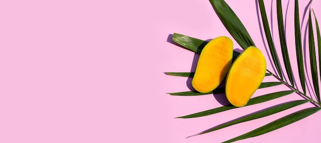 Fruta tropical, rodajas de mango sobre fondo rosa.