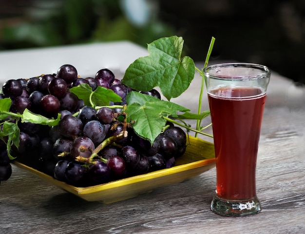 Fruta de uva y vino de uva en el fondo de madera