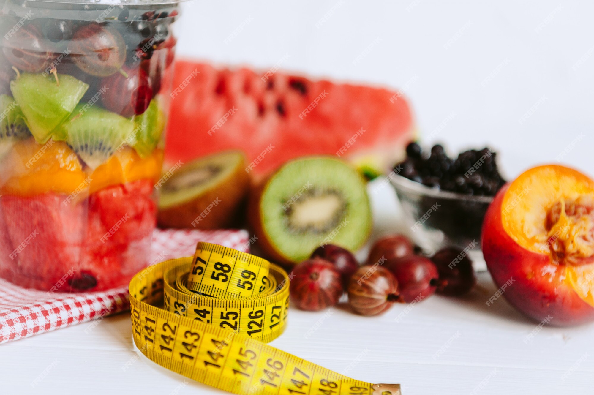 Fruta en un vaso y una cinta para medir el cuerpo.