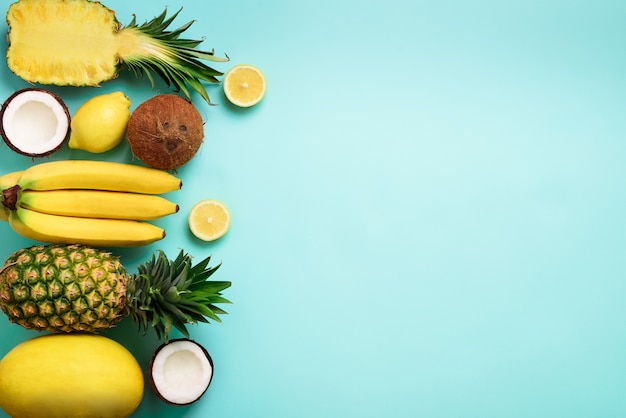 Frutas amarillas orgánicas frescas sobre fondo azul. Concepto monocromático con plátano, coco, piña, limón, melón.