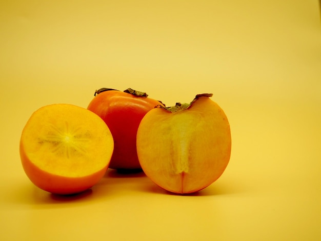 Frutas de caqui frescas cortadas por la mitad aisladas sobre fondo claro