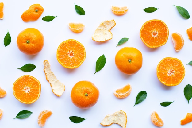 Frutas cítricas anaranjadas frescas con cáscara y hojas verdes en blanco