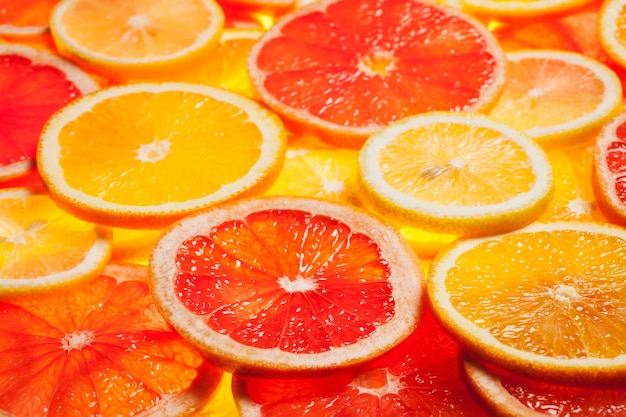 Frutas cítricas coloridas, limão, laranja, fatias de toranja, fundo iluminado