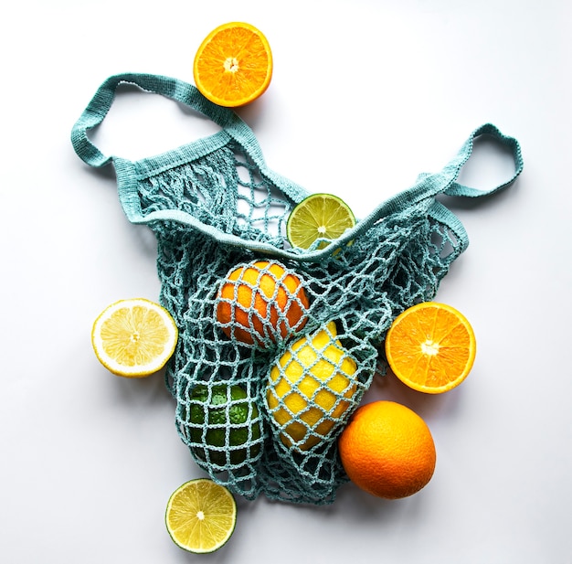 Frutas cítricas enteras maduras en bolsa de hilo