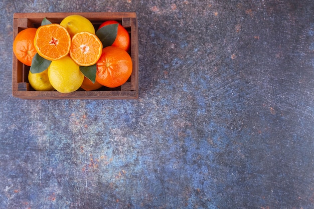 Frutas cítricas frescas com folhas colocadas em uma velha caixa de madeira.