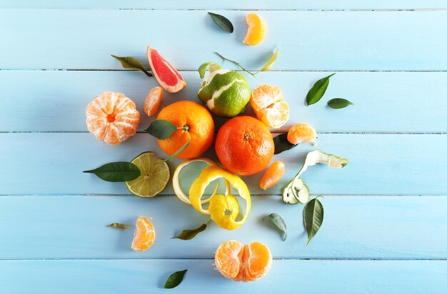 Frutas cítricas frescas con hojas verdes sobre fondo de madera