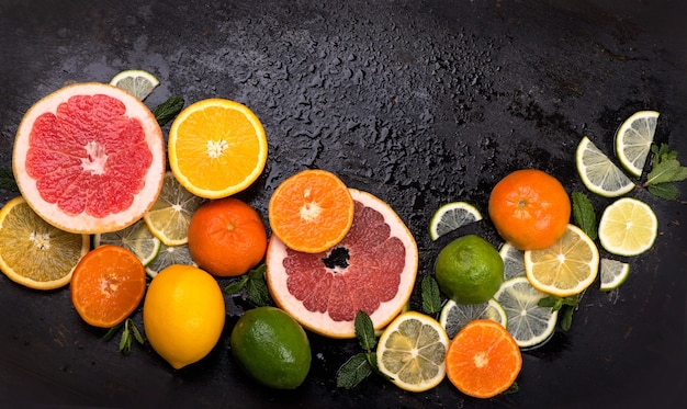Frutas cítricas frescas - Limões, laranjas, limas, toranjas na superfície preta