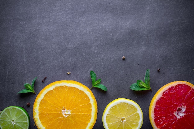 Frutas cítricas frescas, maduras e folhas de hortelã verde sobre fundo escuro. alimentação e dieta saudáveis. copie o espaço