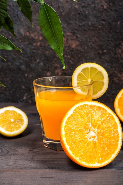 Las frutas cítricas de limón naranja en una canasta y un jugo sobre un fondo oscuro, hacen una dieta de alimentos saludables